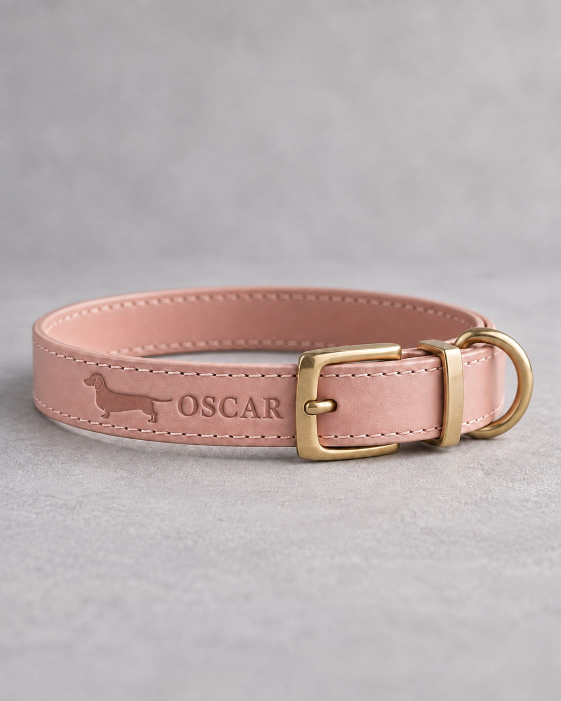 Blush pink leather dog collar debossed with a dachshund silhouette and the name OSCAR, brass pin buckle