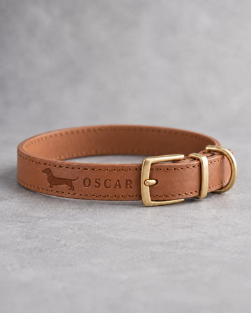 Caramel leather dog collar with a dachshund silhouette and the name OSCAR debossed beside a brass pin buckle
