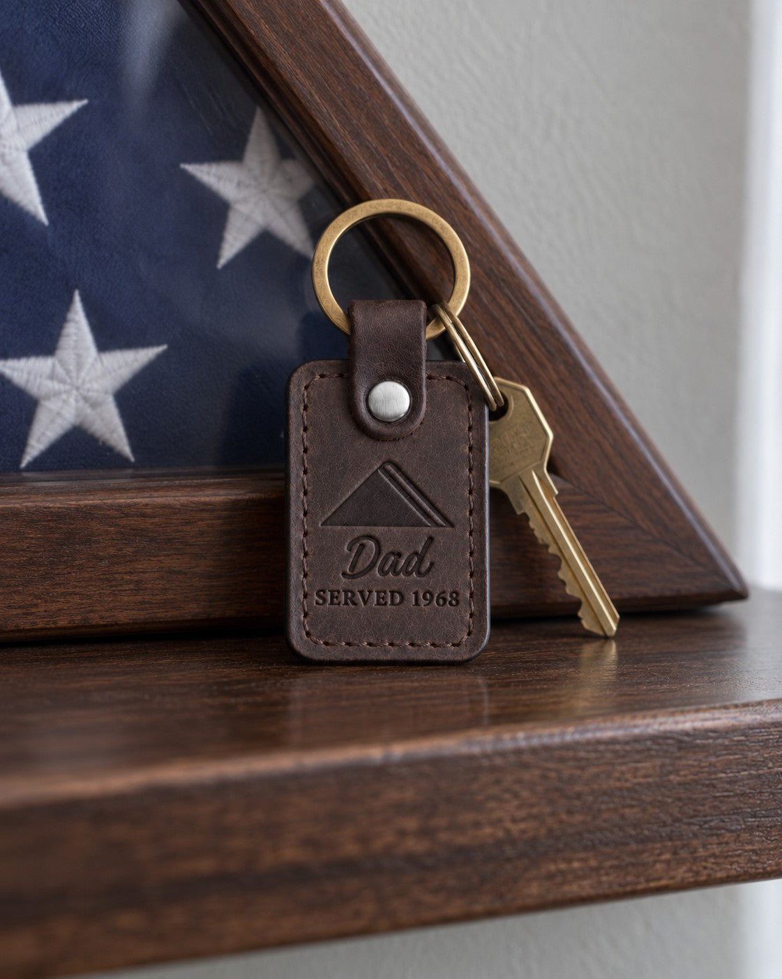 Dark brown Dad Served 1968 keychain on an older man's key ring resting on a wooden mantel