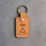 Indian Summer tan leather keychain debossed with a banker's lamp above Dad's and READING CHAIR, on gray concrete