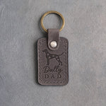 Country gray leather keychain debossed with a Dalmatian silhouette and the words Dally DAD, on gray concrete