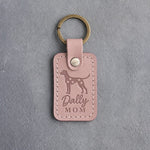 Blush pink leather keychain debossed with a Dalmatian silhouette and the words Dally MOM, on gray concrete