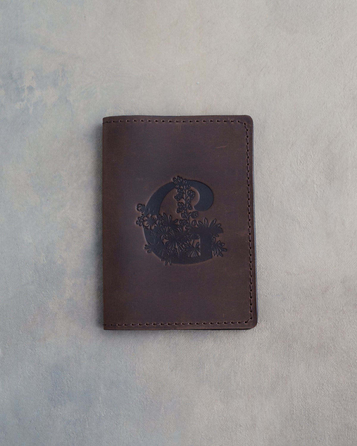 Dark Espresso leather passport cover with a large floral initial C pressed into the front