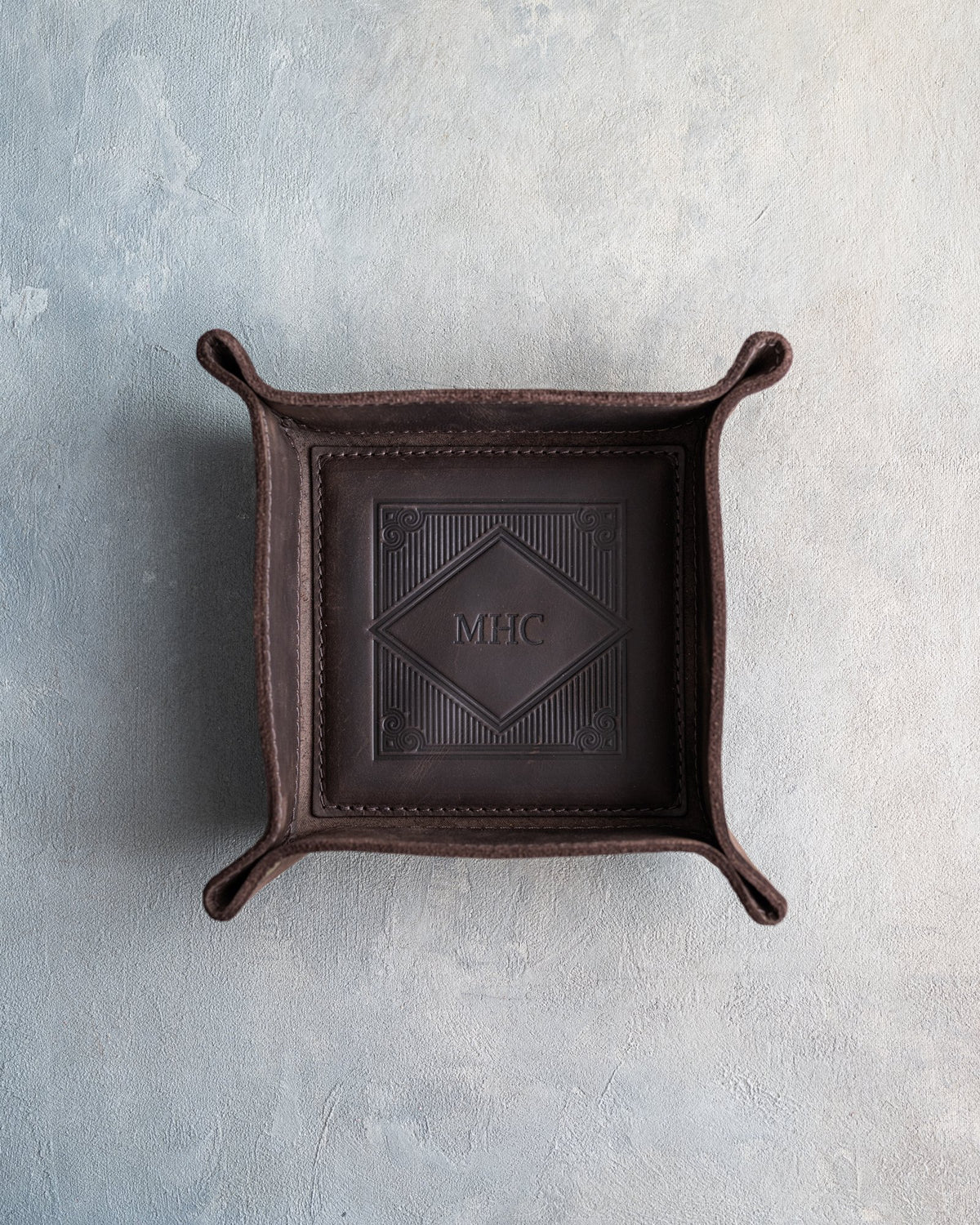 Dark Espresso leather valet tray with snapped corners and the initials MHC pressed into the diamond frame, seen from above