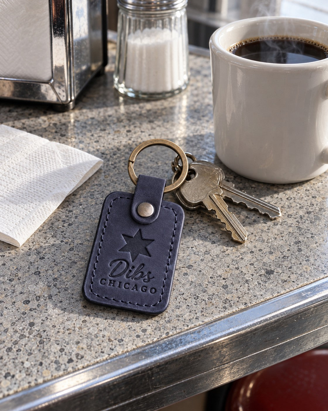 Navy Dibs Chicago keychain on car keys beside a folding lawn chair in a snowy street parking spot