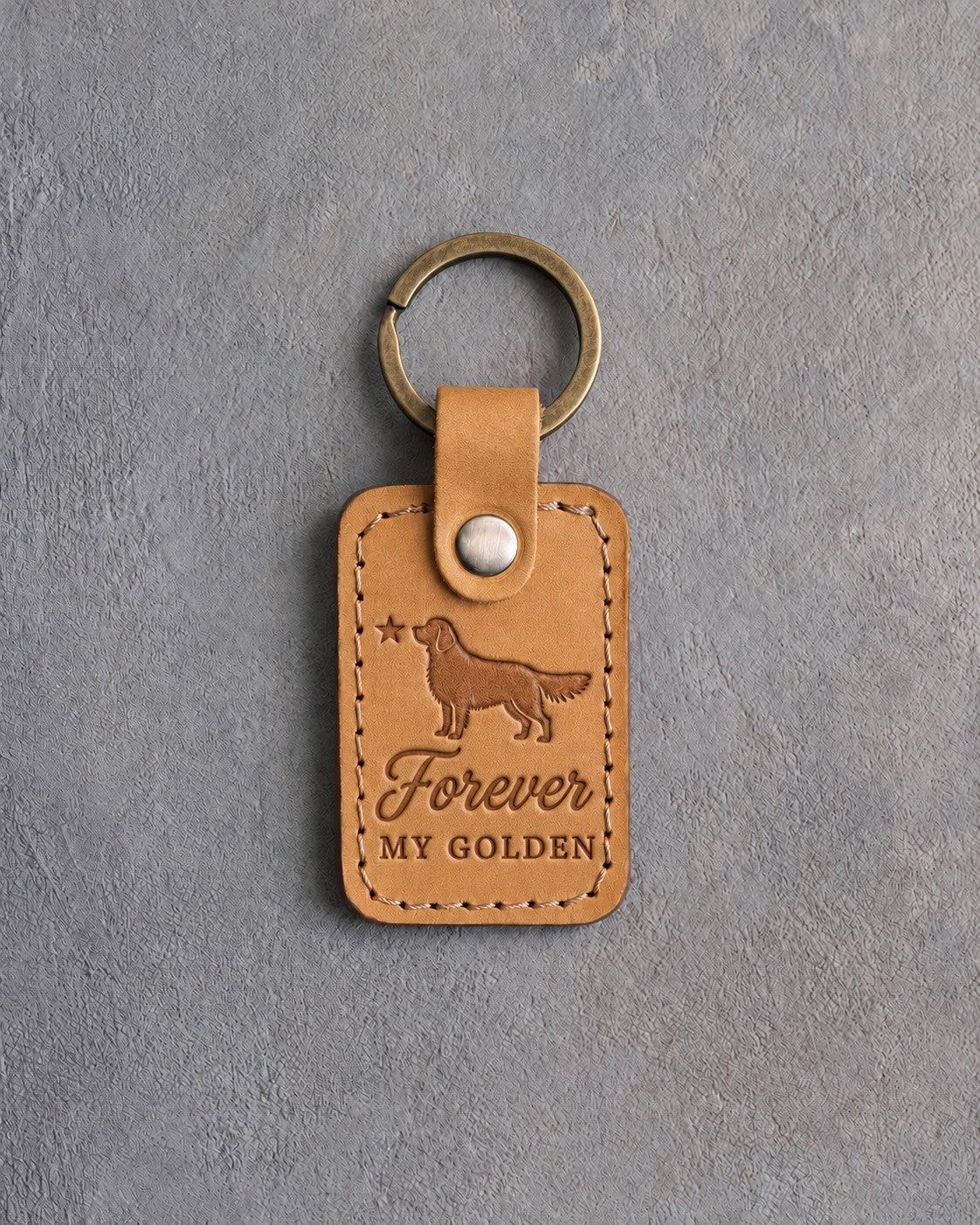 Indian Summer tan leather keychain debossed with a golden retriever and a small star above Forever and MY GOLDEN, on gray concrete