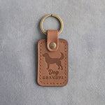 Caramel leather keychain debossed with a standing mixed-breed dog and the words Dog GRANDPA, on gray concrete