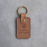 Caramel leather keychain debossed with a single paw print above Always my and BEST FRIEND, on gray concrete