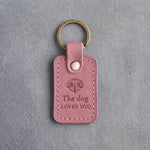 Parisian Blossom pink leather keychain debossed with a dog nose print above The dog and LOVES YOU, on gray concrete