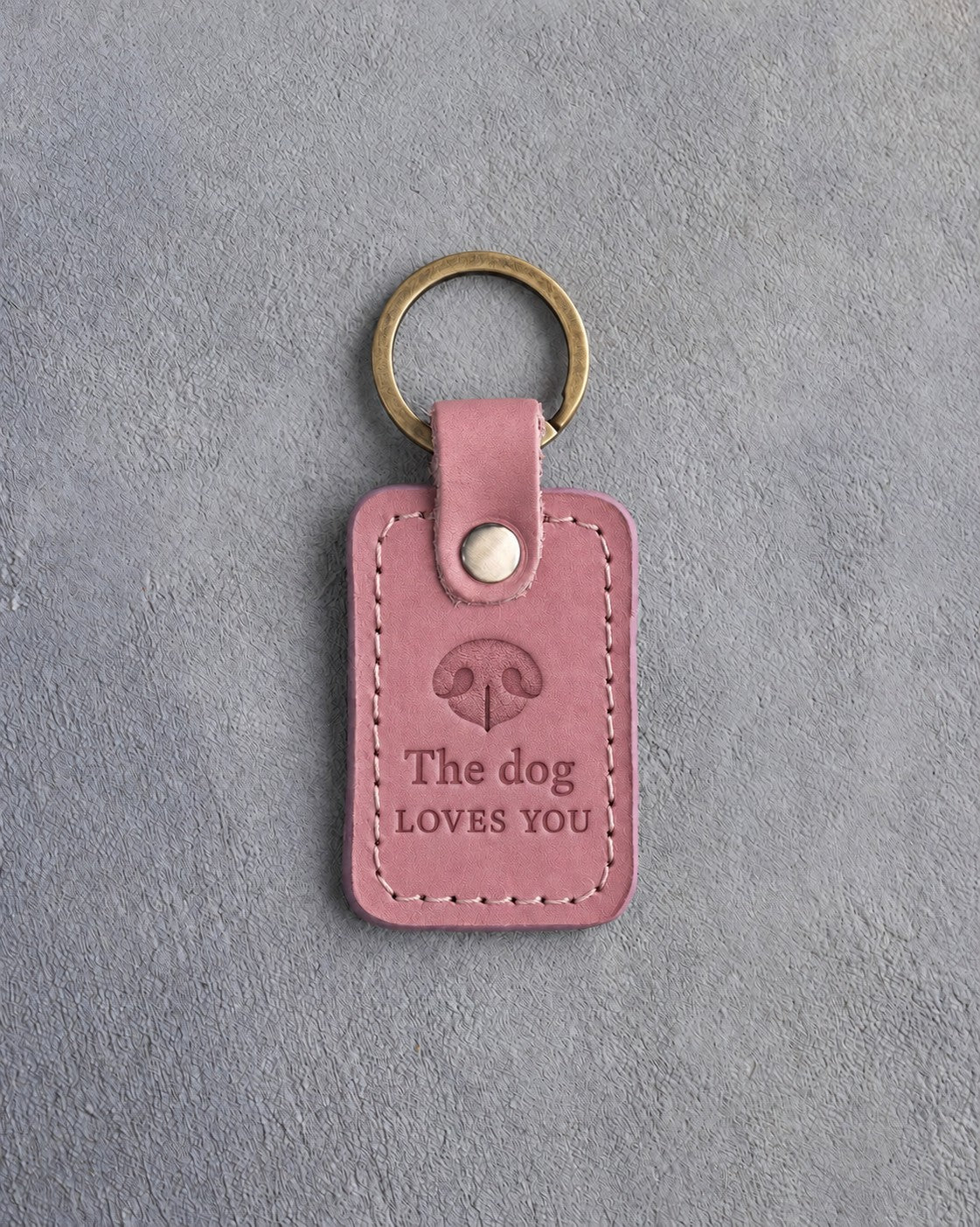 Parisian Blossom pink leather keychain debossed with a dog nose print above The dog and LOVES YOU, on gray concrete