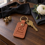 Biscuit DOG OF HONOR keychain in caramel leather on a walnut dresser beside a wristwatch and a boutonniere