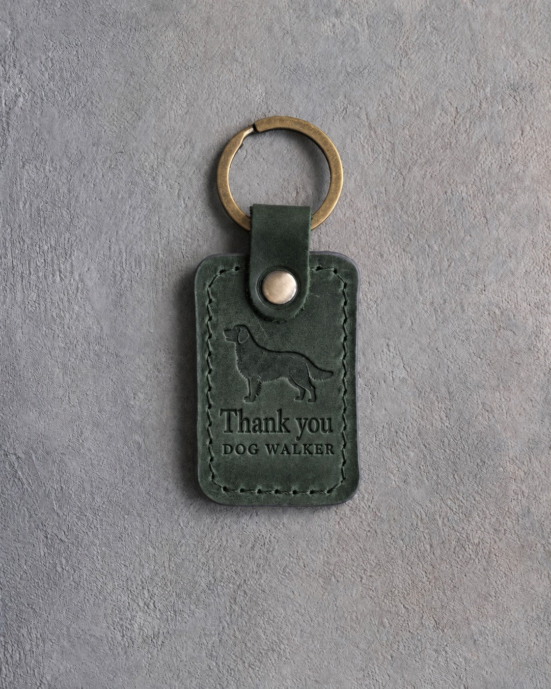 Forest green leather keychain debossed with a golden retriever above Thank you and DOG WALKER, on gray concrete