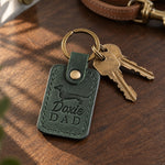 Forest green Doxie Dad keychain with three brass keys on a walnut entry table in late afternoon light