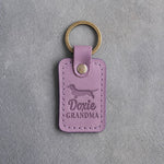 Lilac leather keychain debossed with a dachshund silhouette and the words Doxie GRANDMA, on gray concrete