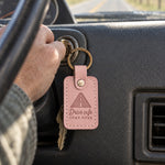 Pink Drive safe COME HOME keychain on car keys beside a front door at dusk