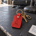 Mia ON DRUMS keychain in bright red leather hanging from a stick bag beside a snare drum