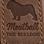 Close-up of Meatball and THE BULLDOG pressed into brown full-grain leather under a stocky bulldog silhouette