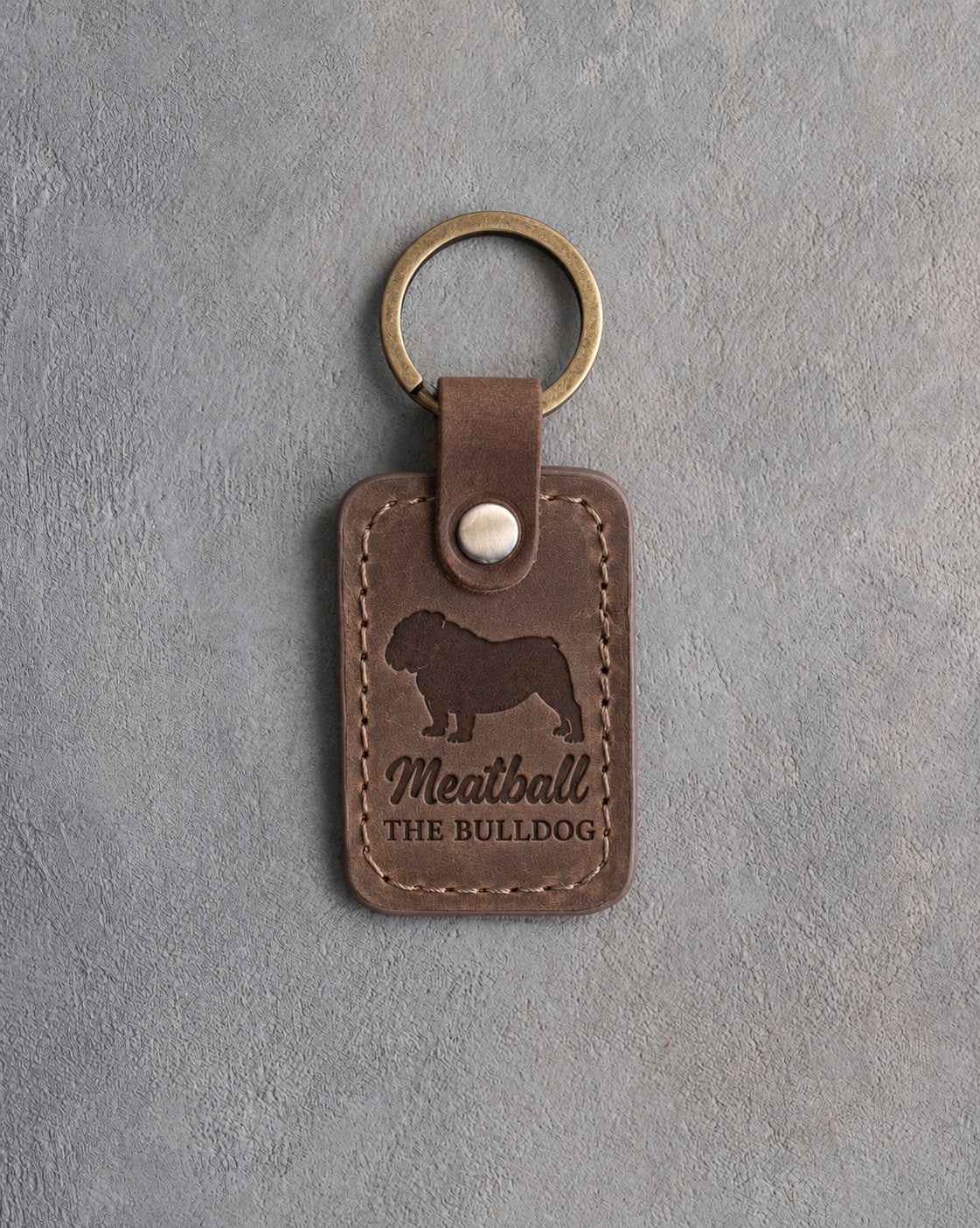 Sicilian brown leather keychain debossed with an English bulldog above the name Meatball and THE BULLDOG, on gray concrete