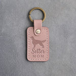 Blush pink leather keychain debossed with an English Setter silhouette and the words Setter MOM, on gray concrete
