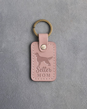 Blush pink leather keychain debossed with an English Setter silhouette and the words Setter MOM, on gray concrete