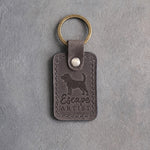 Country gray leather keychain debossed with a beagle silhouette and the words Escape ARTIST, on gray concrete