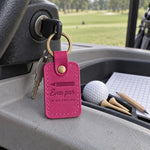 Even Par in My Dreams keychain in bright pink leather on a nightstand beside a folded golf scorecard