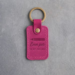 Fuchsia pink leather keychain debossed with a scorecard pencil above Even par IN MY DREAMS, on gray plaster