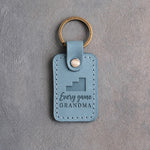 Turquoise leather keychain debossed with stepped bleachers and the words Every game GRANDMA, on gray plaster