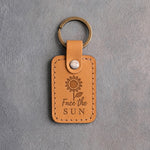 Indian Summer tan leather keychain debossed with a sunflower above Face the SUN, on gray concrete