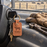 Walker CATTLE keychain in caramel leather on the ignition key of a ranch pickup, work gloves and fence pliers on the dash