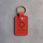 Poppy red leather keychain debossed with a Christmas wreath above The Millers and DECEMBER 2026