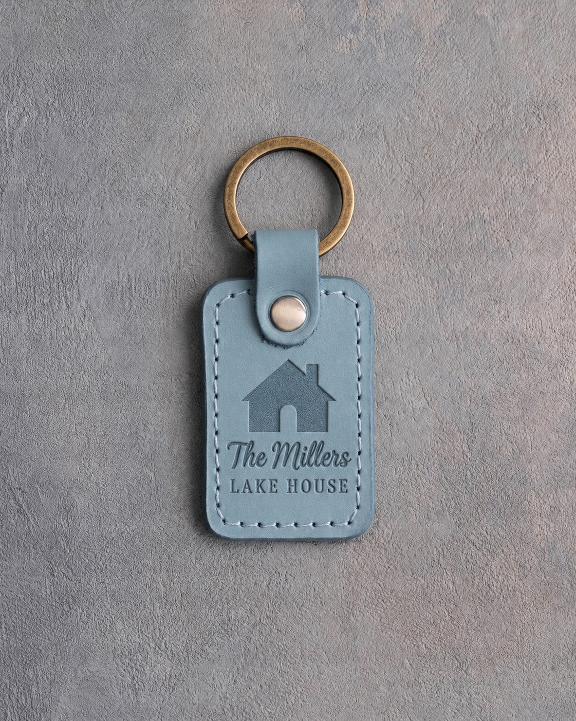 Turquoise leather keychain debossed with a gabled house above The Millers and LAKE HOUSE