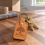 Golden tan The Millers PLANTED 1994 keychain on a key ring among fallen autumn oak leaves
