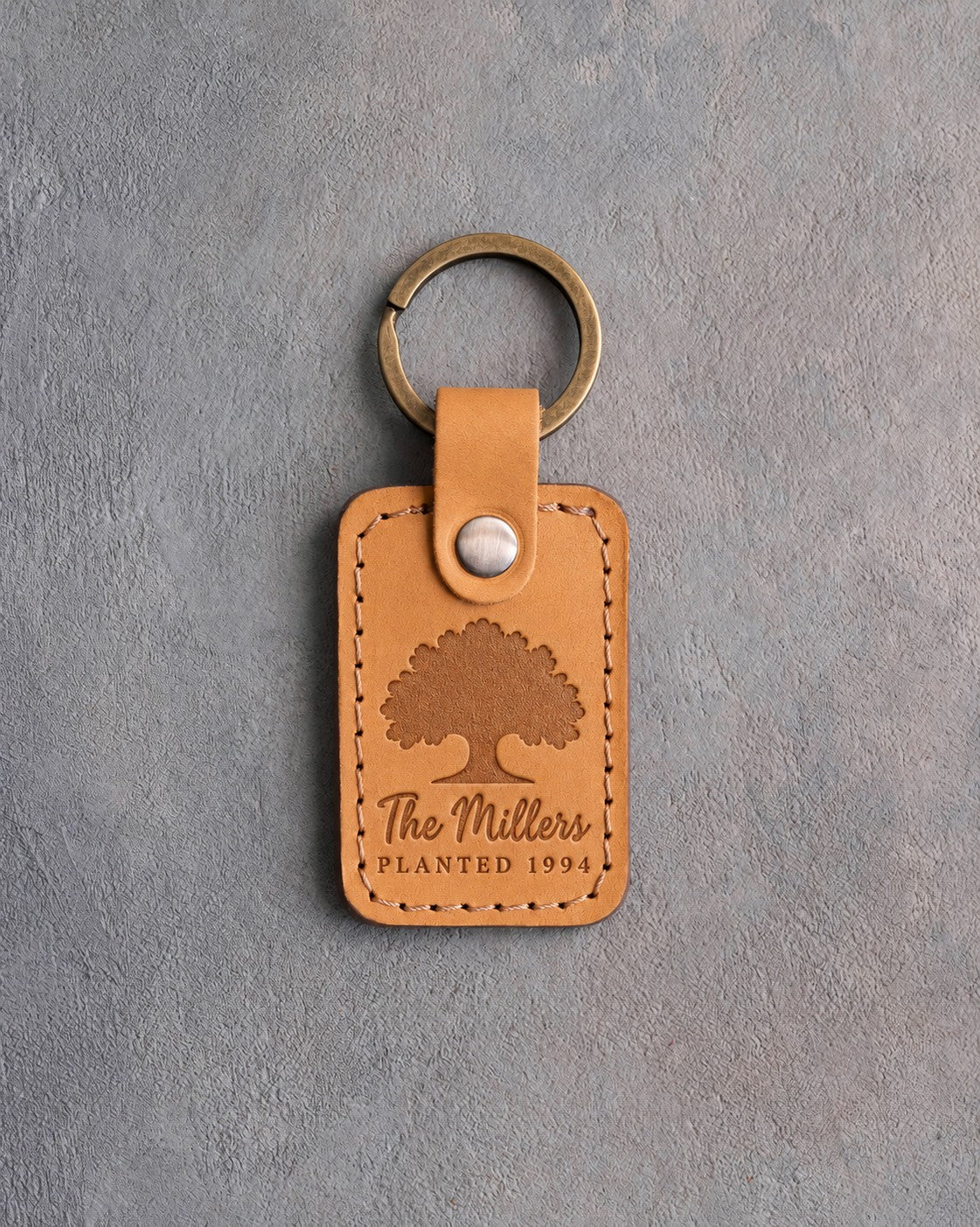 Indian Summer golden tan leather keychain debossed with a solid oak tree above The Millers and PLANTED 1994