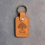 Indian Summer golden tan leather keychain debossed with a solid oak tree above Family and PLANTED IN LOVE, on gray concrete