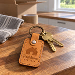 Golden tan First home EST 2026 keychain on a new house key handed across a closing table