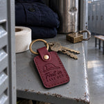 First In Last Out keychain in sangria leather on house keys set down on a station kitchen table beside a coffee mug