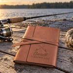 Caramel Garrett FISHING LOG journal in full-grain leather on sun-bleached dock boards beside a spinning rod in low evening sun