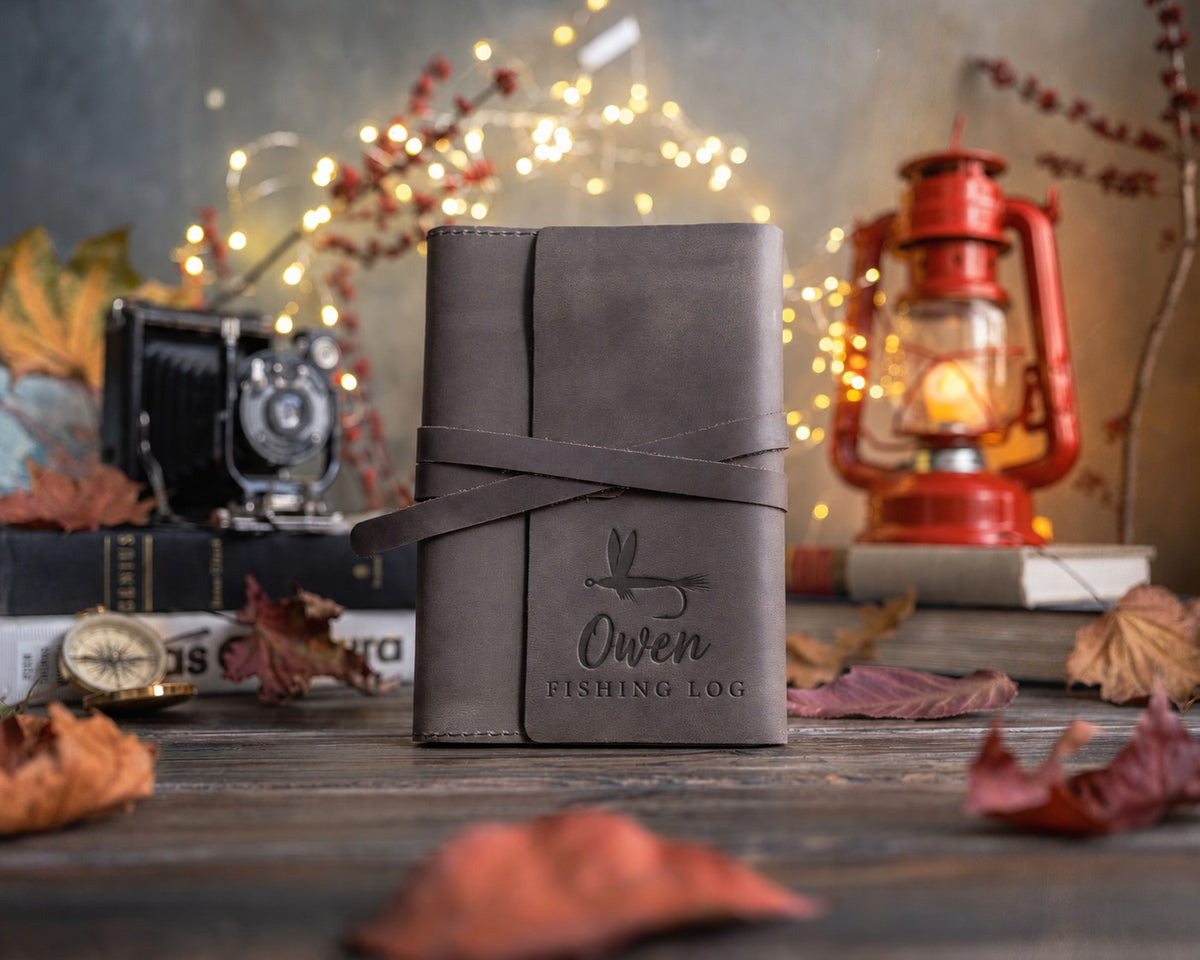 Country gray leather wrap journal with its strap tied, the lower cover debossed with a dry fly above Owen and FISHING LOG