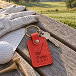 Fore Right keychain in bright red leather hanging from a golf bag beside a driver headcover on a tee box