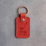 Poppy red leather keychain debossed with a golf driver above the words Fore RIGHT, on gray plaster