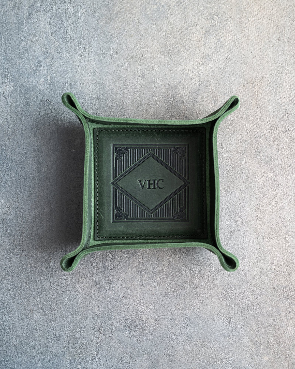 Forest Green leather valet tray with snapped corners and the initials VHC pressed into the diamond frame, seen from above