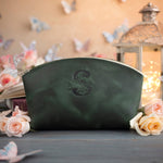 Forest green leather makeup bag with a floral monogram deboss, roses and a lit lantern in the background
