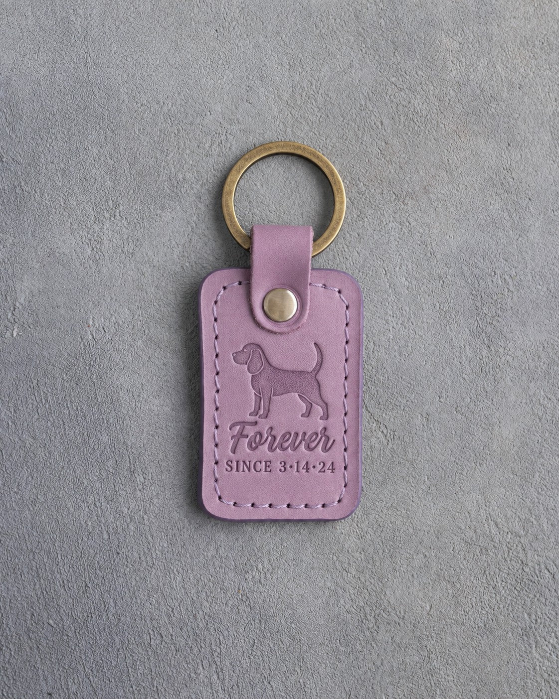 Lilac leather keychain debossed with a dachshund and the words Forever SINCE 3·14·24, on gray concrete