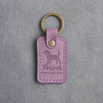 Lilac leather keychain debossed with a beagle and the words Forever SINCE DAY ONE, on gray concrete