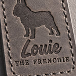 Close-up of the name Louie and THE FRENCHIE debossed in gray full-grain leather under a bat-eared French bulldog