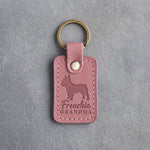 Parisian Blossom pink leather keychain debossed with a French bulldog silhouette and the words Frenchie GRANDMA, on gray concrete