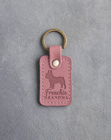 Parisian Blossom pink leather keychain debossed with a French bulldog silhouette and the words Frenchie GRANDMA, on gray concrete