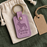 Lilac Frenchie Mom keychain resting on a cotton drawstring pouch on green linen with a kraft gift tag