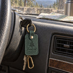 Green Fresh Cut Oregon keychain on truck keys resting on a freshly cut fir tied to a roof rack